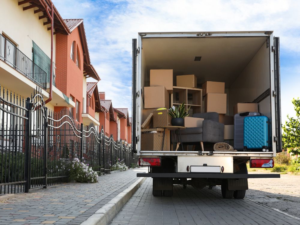 A moving truck full of boxes and furniture parked in front of a house